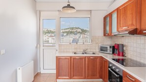 A modern kitchen with wooden cabinets, a stainless steel sink, a microwave, and an oven. - Penthouse w Acropolis View & Parking (Athens)