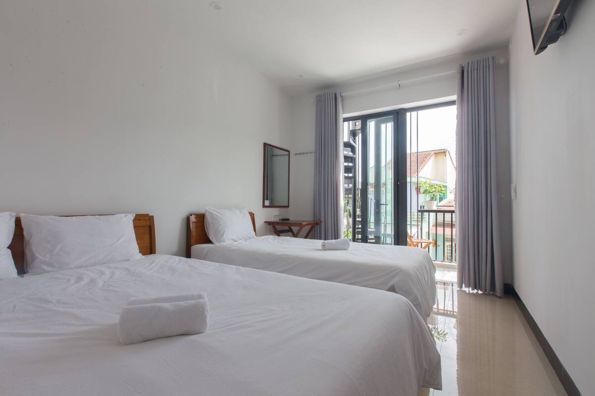 Ein Hotelzimmer mit zwei Betten, einem kleinen Tisch und Blick auf den Balkon.