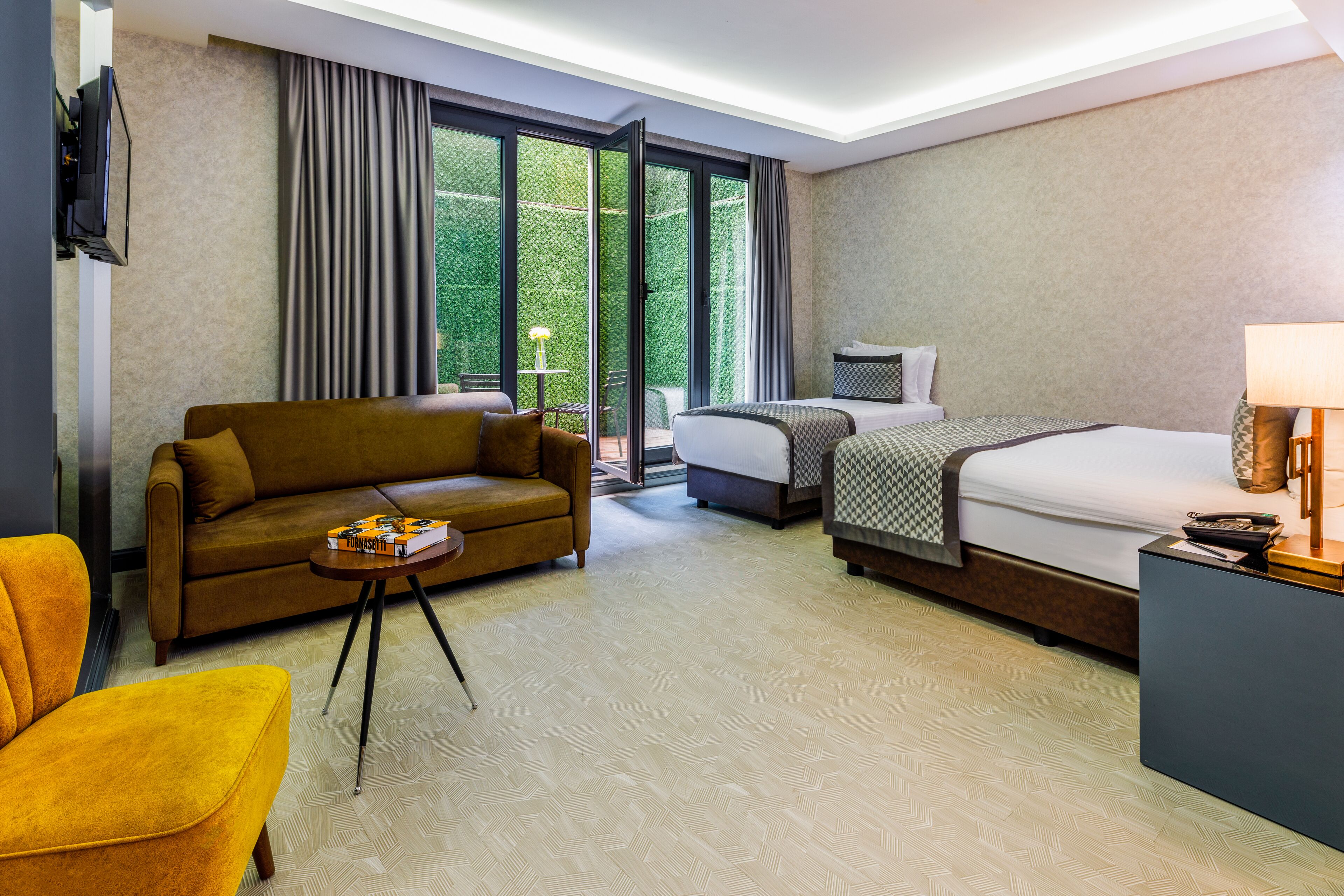 Ein Hotelzimmer mit Sofa, Bett, Schreibtisch und Fernseher.