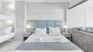 Quarto de hotel moderno com uma cama grande, um sofá e uma mesa de cabeceira com luminárias.
