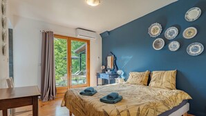 Een slaapkamer met een bed, een bureau, een stoel, een dressoir en een raam met gordijnen.