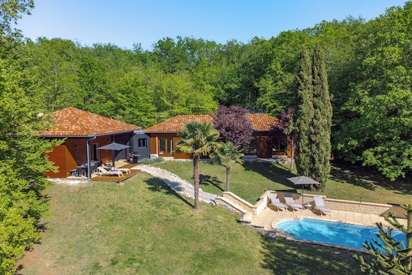 A residential property with a swimming pool, patio furniture, and a stone pathway.