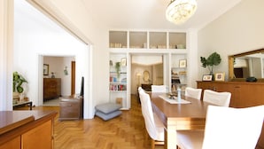A spacious dining area with a wooden table and white chairs, flanked by white shelving units and a large mirror. - Your home under  Acropolis Central& safe (Athens)