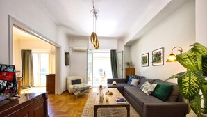 A living room with a sofa, coffee table, and a TV stand with a magazine rack. - Your home under  Acropolis Central& safe (Athens)