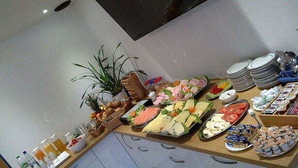 A buffet table with various food items, including fruits, cheeses, and pastries. - Pension am Meer (Norden)