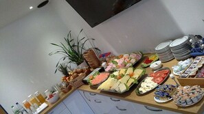 A buffet table with various food items, including fruits, cheeses, and pastries. - Pension am Meer (Norden)