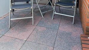 A covered patio area with two metal-framed chairs and a small round table. - Pension am Meer (Norden)