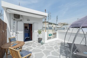 A rooftop terrace with a wooden table and chairs, a potted plant, and a covered seating area. - Island in the sky Acropolis & city views (Athens)