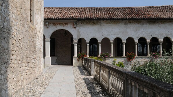 A courtyard with a tiled roof, stone walls, and a series of arches.