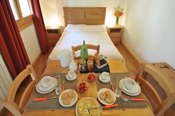 Una preparación para el desayuno con una mesa de madera, sillas y una cama con cabecero de madera.