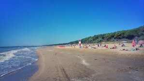 Una playa con una torre de salvavidas, sombrillas y gente relajándose.