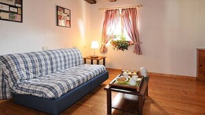 Una habitación acogedora con un sofá azul, una pequeña mesa de madera con una bandeja de comida y una ventana con cortinas.