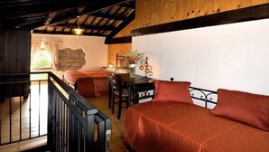 Una habitación acogedora con cama, escritorio y silla. Tiene una ventana con cortinas y vistas al verde exterior.