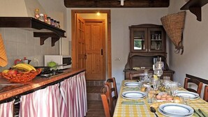 Zona de menjador amb una taula preparada per a quatre, una barra de cuina amb cistell de fruita i un armari de fusta amb portes de vidre.