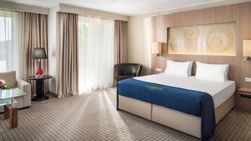 Una habitación de hotel con una cama grande, un escritorio, una silla y una lámpara.