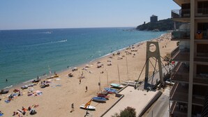 A beach with a large building on the right, a pier, and a clear sky. - Exceptional location, 1st line of the sea, 86m2 apartment with terrace (Sant Antoni de Calonge)