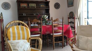 A living room with a dining table, two chairs, a bookshelf, and a window with curtains. - Exceptional location, 1st line of the sea, 86m2 apartment with terrace (Sant Antoni de Calonge)