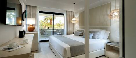 A modern hotel room with a large bed, a desk with a coffee maker, a chair, and a balcony with a view of palm trees.