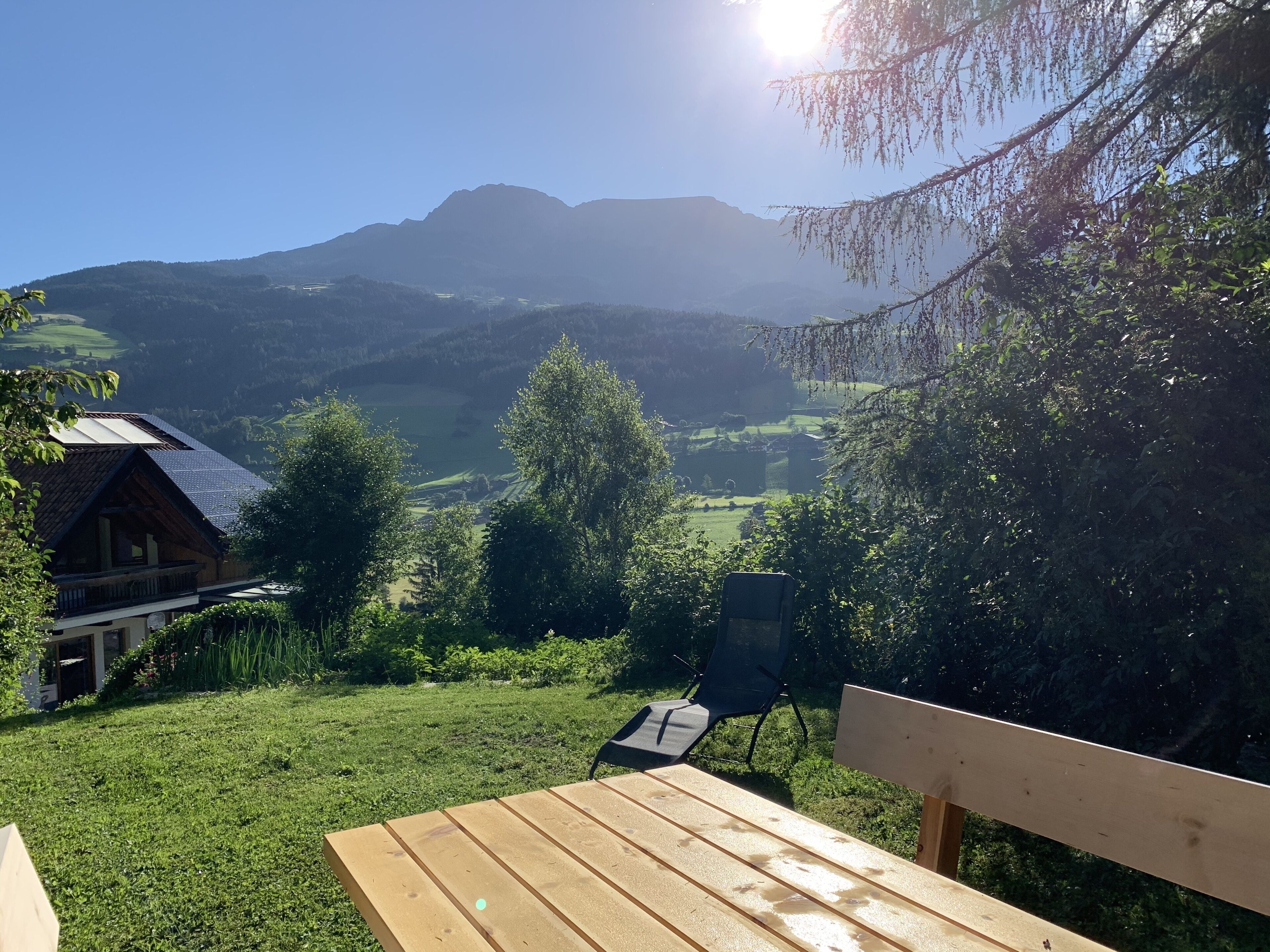 Ein Holztisch und eine Bank in einem Garten mit Blick auf die Berge.