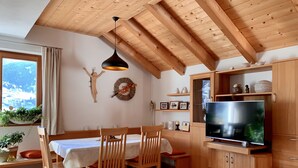 A cozy dining area with wooden furniture, a TV, and a view of the outdoors. - Apartment HaNiLe with "honeymoon suite" with dream view - max. 14 pers (Sarnthein)