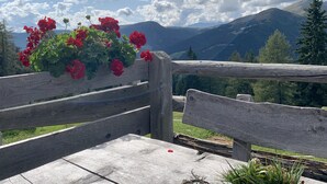 A wooden bench with a flower arrangement and a view of mountains. - Apartment HaNiLe with "honeymoon suite" with dream view - max. 14 pers (Sarnthein)