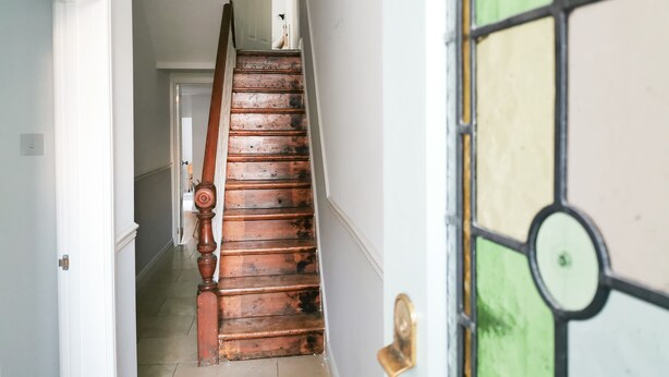 A wooden staircase with a black pendant light, leading to a room with a green and yellow stained glass door. - Railway Street by Switchback Stays (Cardiff)