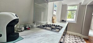 A kitchen with a gas stove, a coffee maker, and jars on the counter. - Railway Street by Switchback Stays (Cardiff)