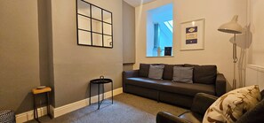A living room with a sofa, a small table, a lamp, and a framed book on the wall. - Railway Street by Switchback Stays (Cardiff)