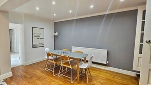 A room with a dining table, chairs, a radiator, and a framed quote on the wall. - Railway Street by Switchback Stays (Cardiff)