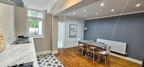 A modern kitchen with a marble countertop, a dining area with a table and chairs, a window with a view, and a framed quote on the wall. - Railway Street by Switchback Stays (Cardiff)