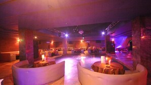 A dimly lit lounge area with cushioned seating and a central table, featuring ambient lighting and a disco ball. - Atlantique Panorama (Safi)