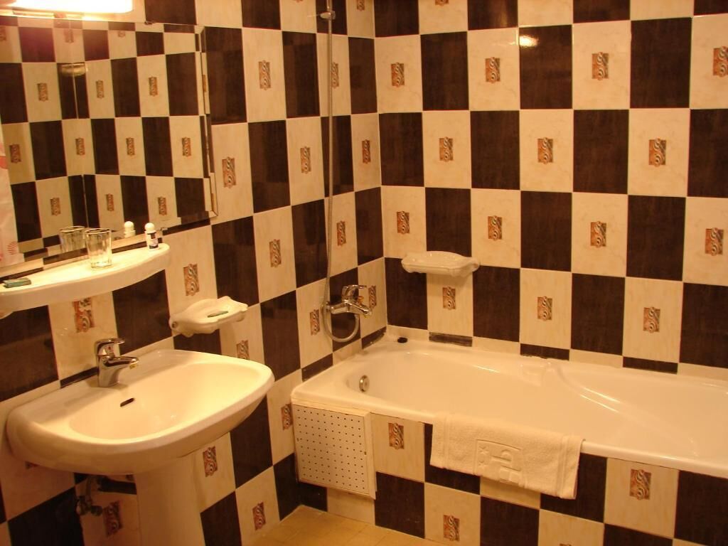 A bathroom with a checkered tile backsplash, a sink, and a bathtub.