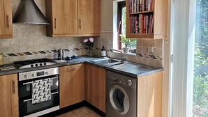 Una cocina compacta con armarios de madera, estufa, horno y lavadora.