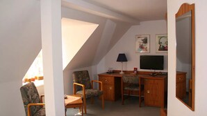 Una habitación con un escritorio, dos sillas, un televisor y un espejo.