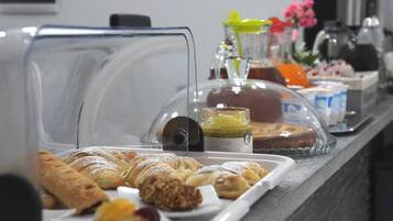 Un bufé de desayuno con pastelería, una máquina de café y aderezos.