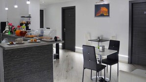A modern dining area with a central island, black chairs, and a table with a small plant. - B&B Agrigento da Tony Palermo (Agrigento)
