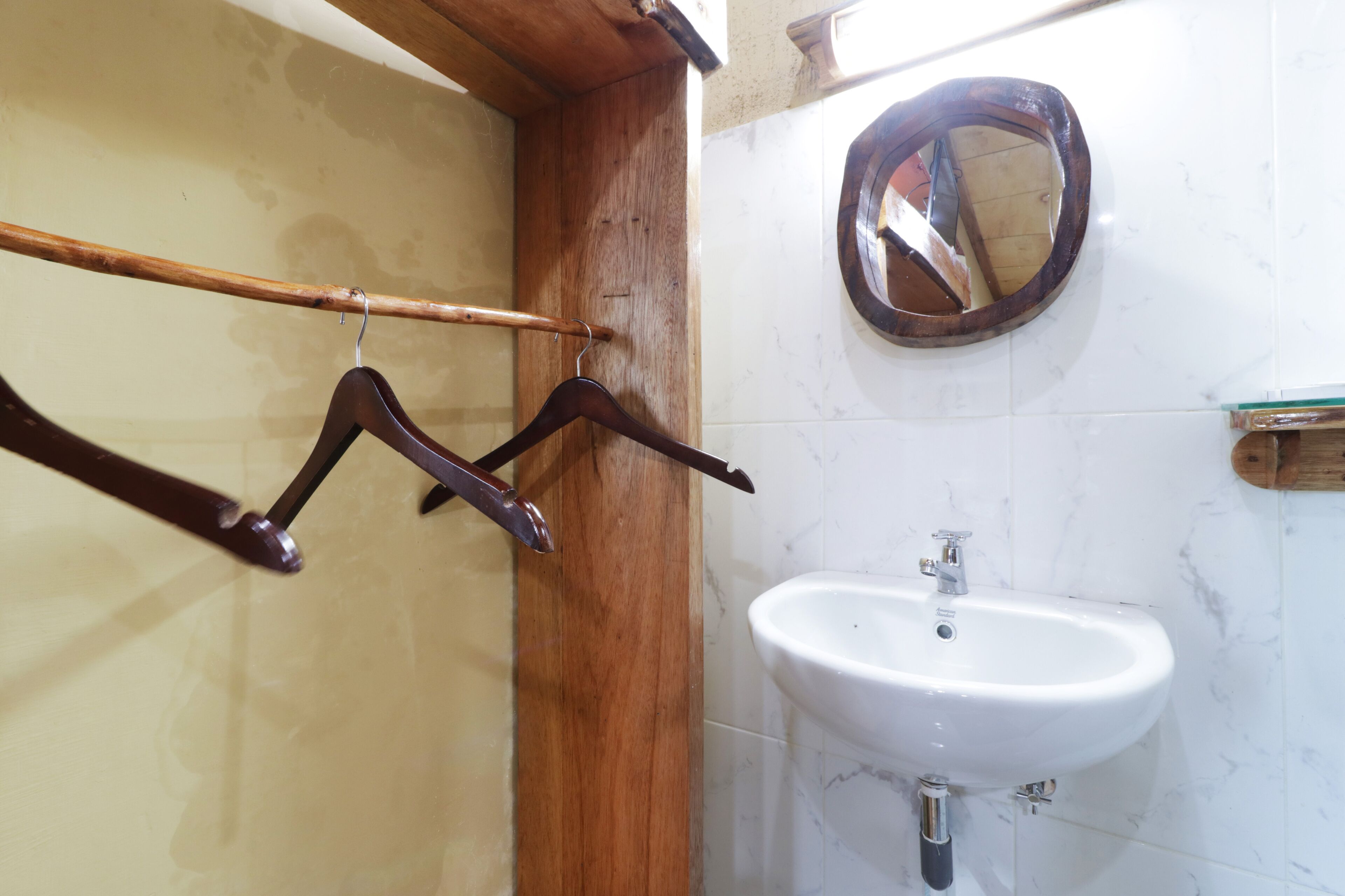 Un baño con tocador de madera, lavabo blanco y espejo.
