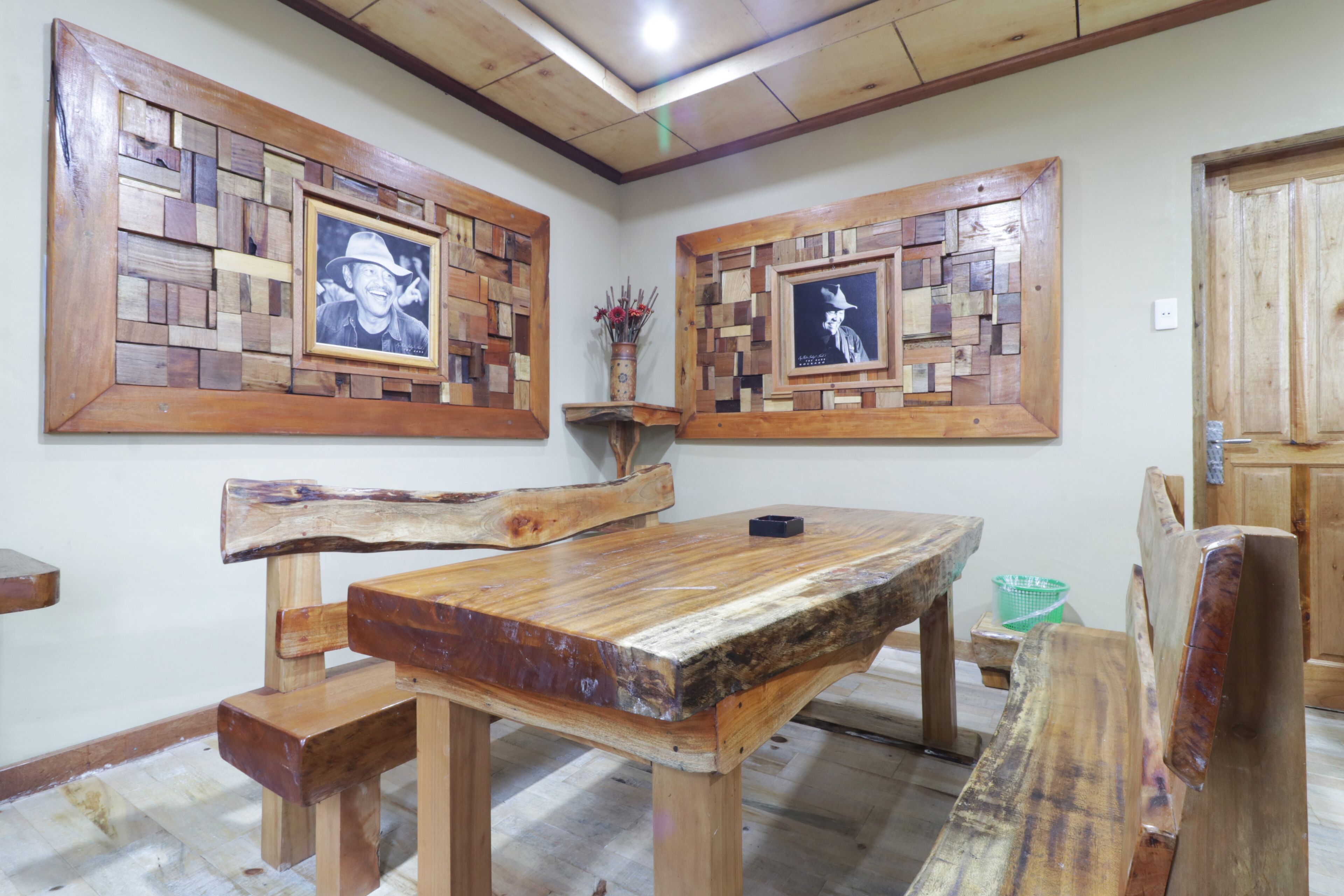A rustic wooden dining table with benches, surrounded by wooden wall art.