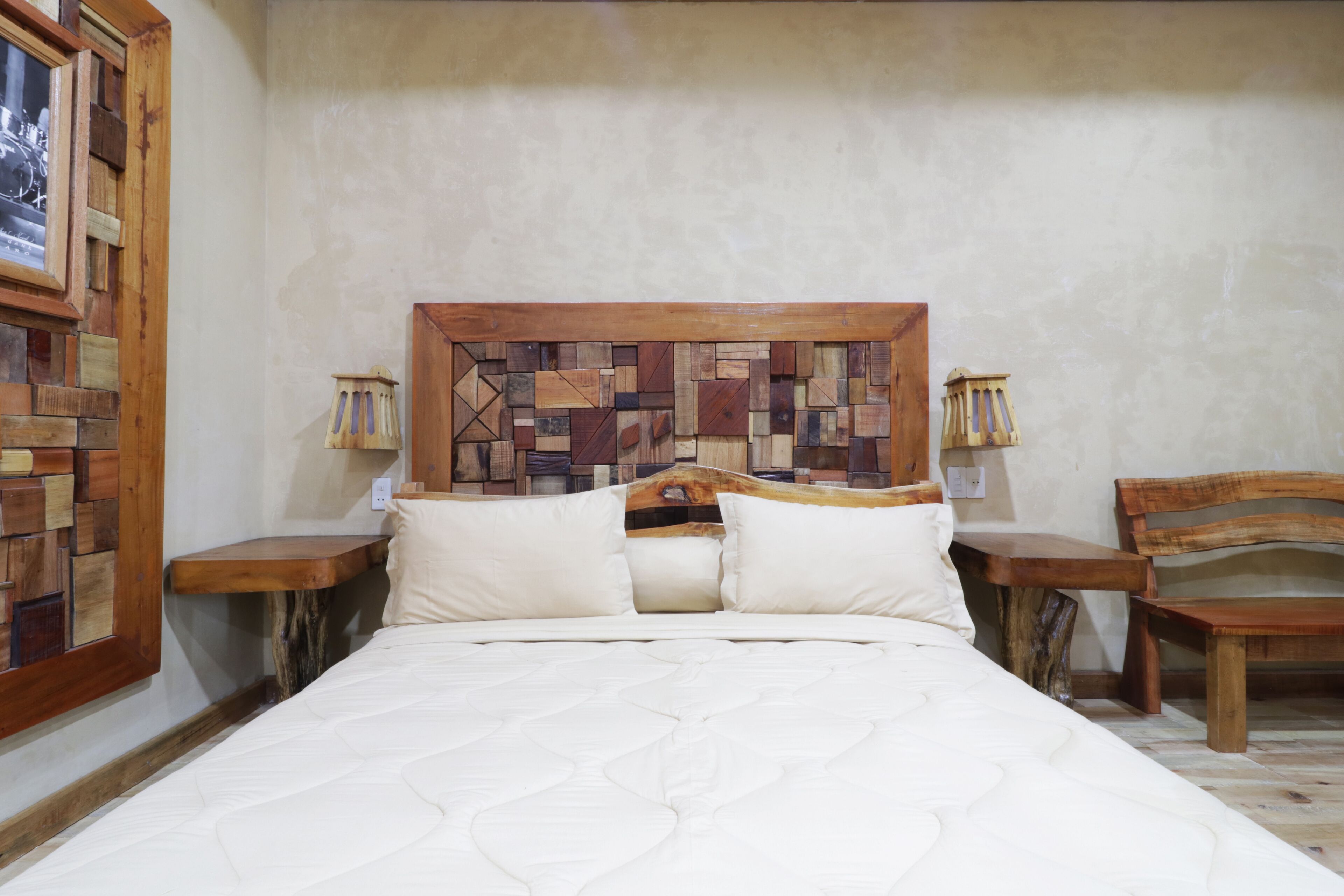 Un lit avec une tête de lit en bois, deux tables de chevet et une chaise en bois.