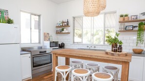 A modern kitchen with white cabinetry, a wooden island with bar stools, and a large window providing natural light.