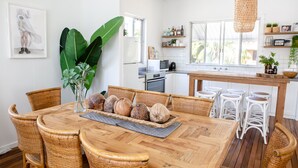 A dining area with a wooden table, wicker chairs, and a central island with stools.