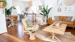 A spacious living room with a wooden dining table, two wicker chairs, a sofa, and a coffee table.