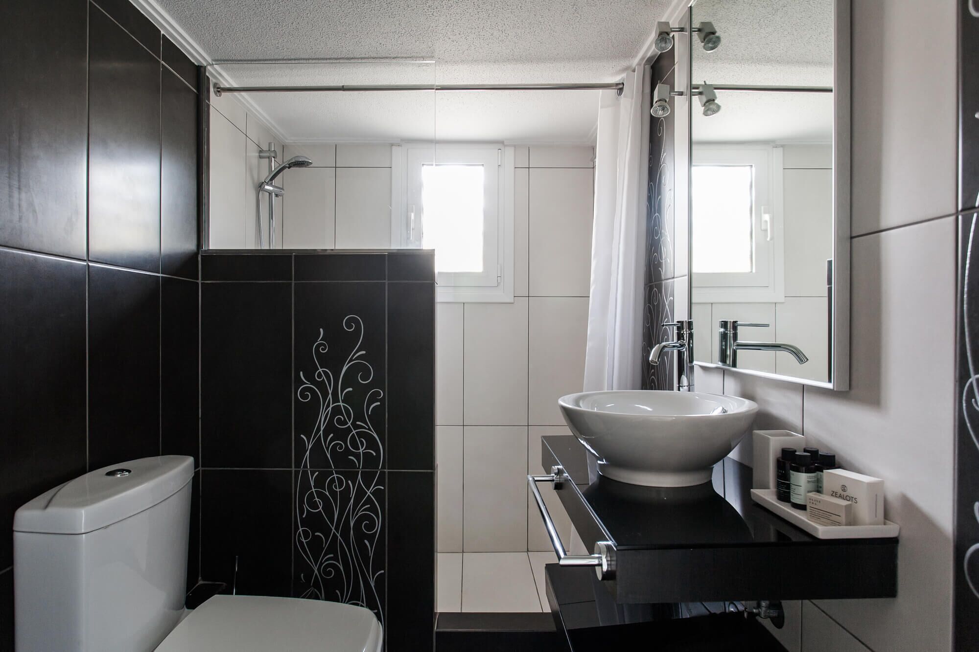 A modern bathroom with a black and white tiled design, a white sink, and a toilet.