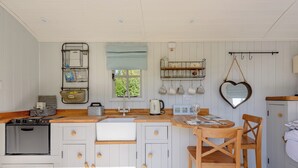 Une cuisine avec des armoires blanches, un plan de travail en bois, un évier, une cuisinière et un coin repas comprenant une table et des chaises en bois.