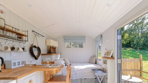 Une cuisine compacte avec un coin repas, un lit et une petite table sur laquelle se trouve une bouteille.