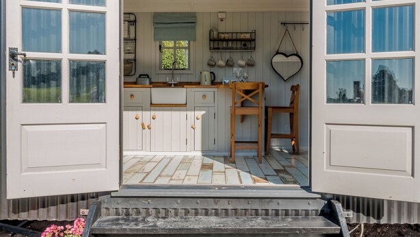 Une cuisine avec des meubles blancs, un plan de travail en bois et une fenêtre donnant sur un paysage verdoyant.