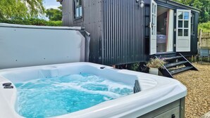 Un chalet confortable doté d’un bain à remous, d’une façade en bois et d’une porte donnant sur une chambre.