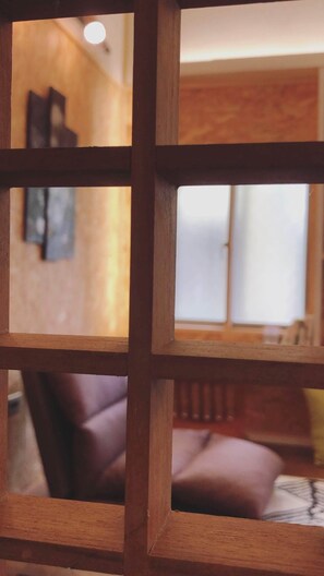 A room with a wooden partition, a sofa, and a window. - Shadow House (Tainan)