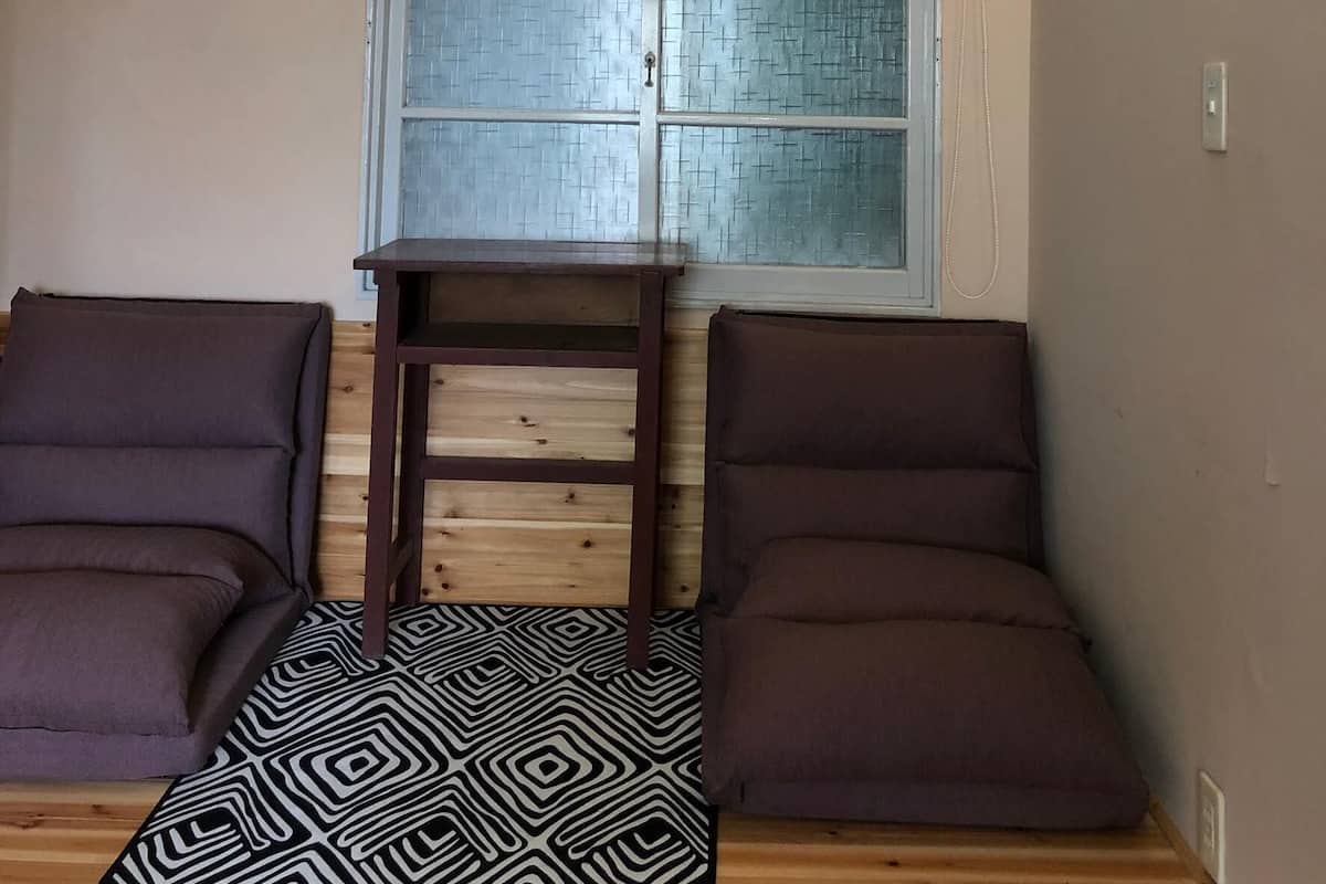 A room with a window, a small table, two sofas, and a patterned rug.
