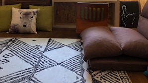 A cozy living room with a wooden wall, a window with frosted glass, a red lamp, a sofa, and a patterned rug. - Shadow House (Tainan)